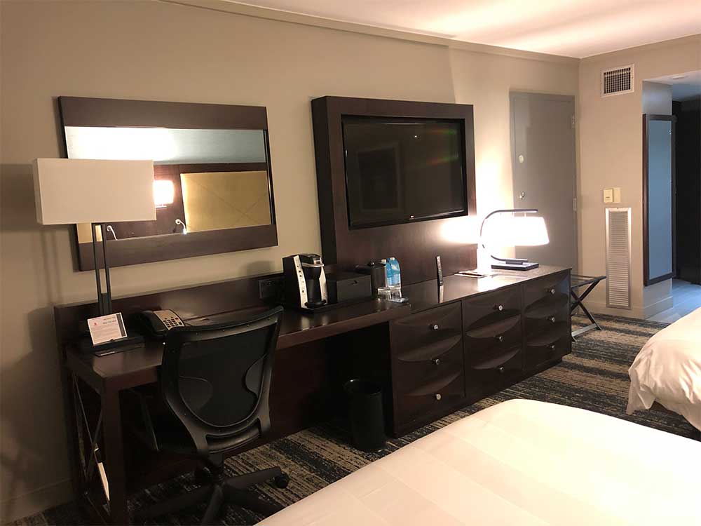 TV and desk across from beds in hotel room.